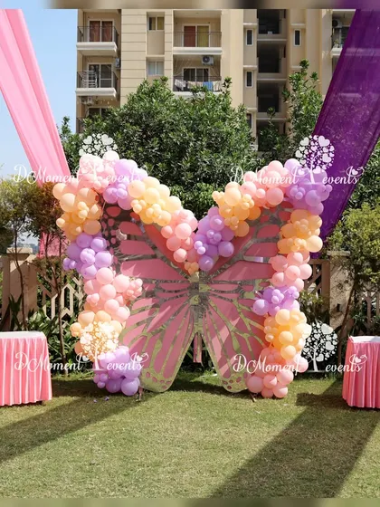 A stunning butterfly-shaped photo point made of pastel balloons serves as a perfect centerpiece for an outdoor garden party.