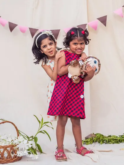 Playtime is better together. These sisters are having a blast in their coordinated dresses, showing off their unique personalities while still looking like a perfect pair.