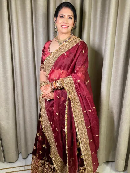 Beauty in red for the mother of the bride. She looks absolutely radiant and happy in a classic red and gold outfit, with makeup that is both elegant and age-appropriate.