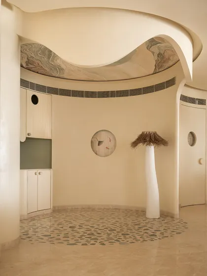 The coffee corner at Soft Serve, with its pebble-like floor inlay and a sculptural floor lamp. The ceiling features a custom art piece.