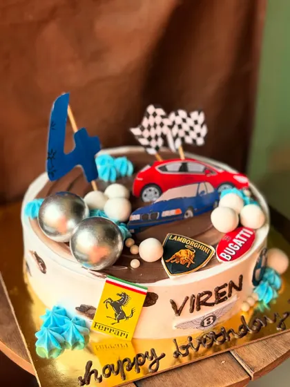 A cake for a little car enthusiast, featuring logos from Ferrari, Lamborghini, and Bugatti. The road on top is made from chocolate, perfect for racing the toy car toppers.