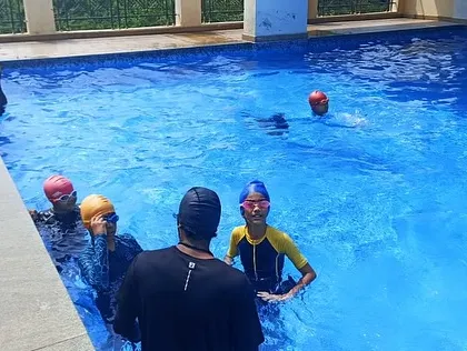 A group of young swimmers listens to their coach at the edge of the pool, ready for their next lesson.