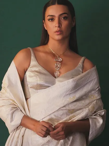 A frontal view of the elegant white saree, showcasing the unique carved necklace. The minimal styling allows the statement jewellery and the texture of the handloom saree to shine.