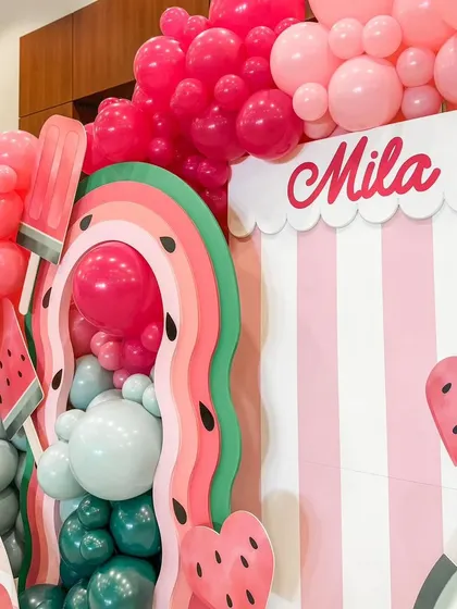 The vibrant colors of the "One in a Melon" theme are on full display here. The layered, wavy backdrops in pink and green mimic the look of a watermelon slice, creating a fun and cohesive design.