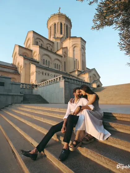 A romantic portrait of a couple on the steps of a grand cathedral in Georgia at sunset. The golden light and historic architecture create a timeless and elegant pre-wedding photograph.