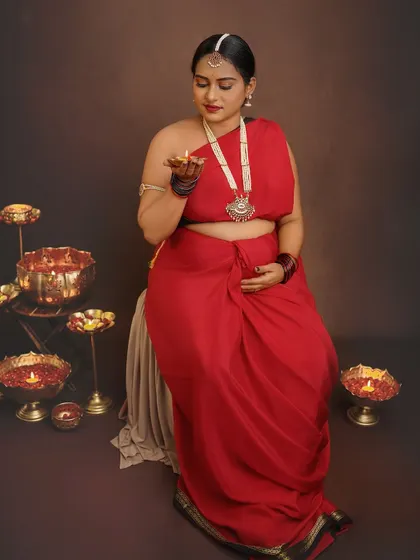 Holding a diya, the lamp of life, this portrait is rich with symbolism. The warm glow illuminates her face, creating a serene and deeply traditional maternity photo.