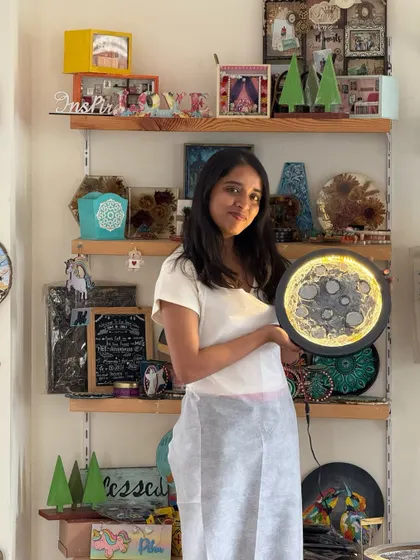 A participant beaming with pride as she holds her finished moon lamp. The warm glow adds a magical touch to her creation.