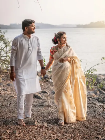 An expecting couple holds hands while looking out towards the horizon during their lakeside photoshoot. This image evokes a sense of shared dreams and the future they are building together.
