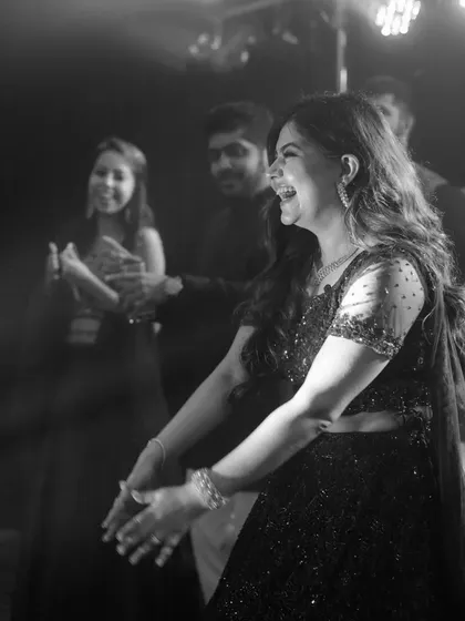 A candid black and white shot of the bride laughing and dancing at her cocktail party.