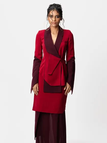 A full-length view of a high-fashion look for a designer brand. I created a messy, artistic updo with loose, wet-look tendrils to complement the structured, two-tone red blazer.