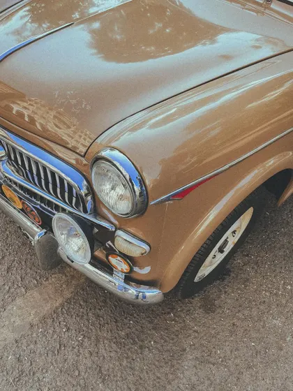 A close-up of a classic Fiat, showcasing its distinctive grille and extra headlights, ready for a rally.