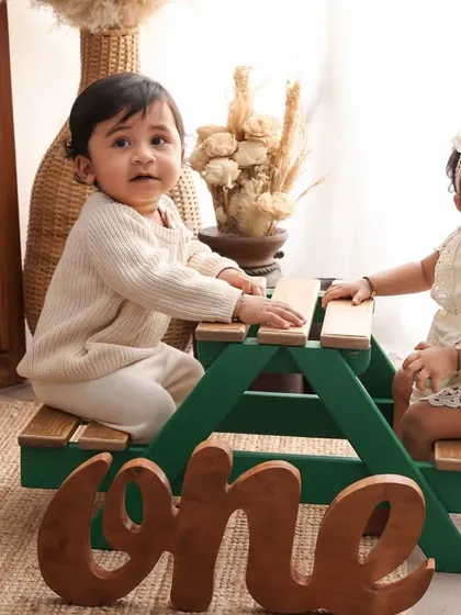 Double the cuteness. This first birthday shoot for twins features a miniature picnic bench and a wooden "one" sign, creating an adorable and memorable setup.
