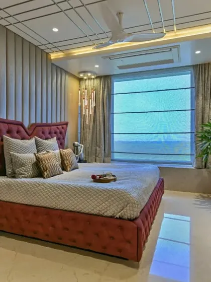 This bedroom features a dramatic winged headboard in a rich burgundy velvet. The design is complemented by a geometrically patterned ceiling and a sleek, modern dresser, creating a look of pure luxury.
