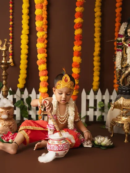 This little Krishna is busy playing with his pot of butter, creating a charming and authentic scene.