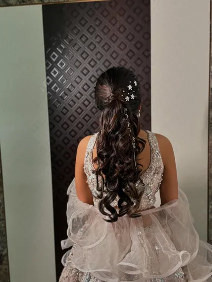 Sparkling star accessories in a curly ponytail for a magical sangeet night hairstyle.