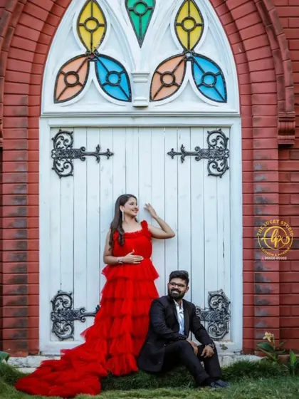 A stylish pre-wedding shoot with an architectural backdrop. The groom's all-black suit provides a modern, sleek contrast to her vibrant red ruffled gown.