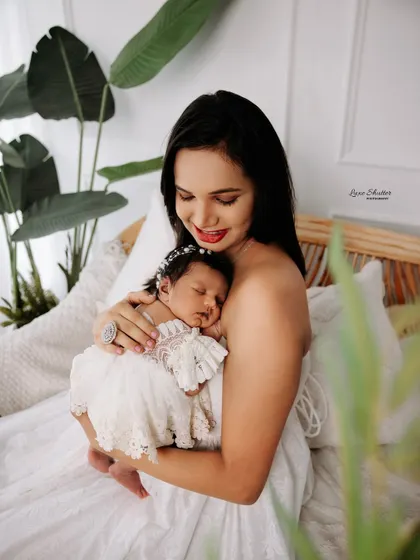 A mother lovingly gazes at her sleeping newborn, held securely in her arms. The soft, natural light enhances the tenderness of the moment.