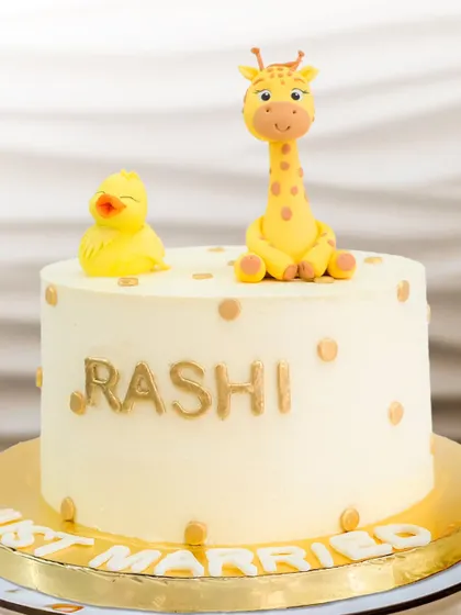 Celebrating cute beginnings after "I Do". This whimsical "Just Married" cake features adorable, handcrafted giraffe and duckling toppers and a touch of gold.