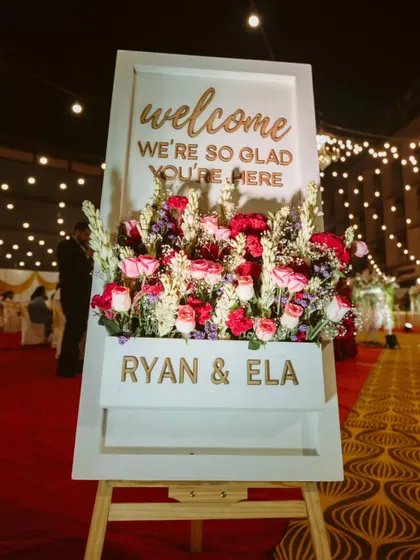 A warm and personal welcome for guests. This custom welcome sign, adorned with a beautiful floral arrangement, sets a gracious and inviting tone for the reception.