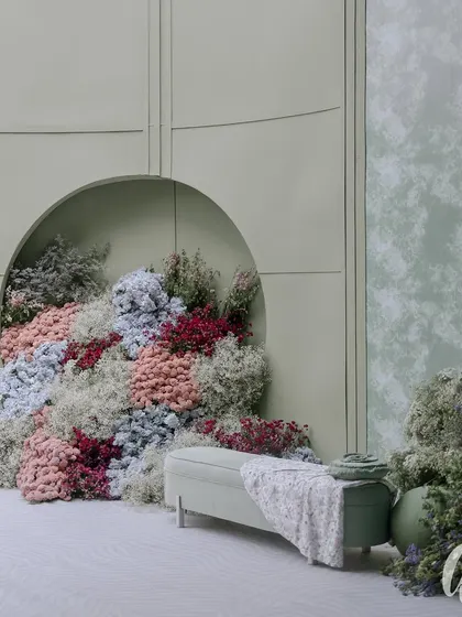 A dedicated photo corner featuring a bench set against a wall with a circular nook overflowing with dyed baby's breath. This provides a stunning and artistic backdrop for guest photos.