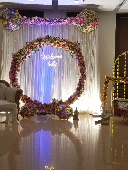 For a more elegant and sophisticated baby shower, I can create a large ring frame covered in beautiful artificial flowers. The glowing 'Welcome baby' sign adds a warm and inviting touch.