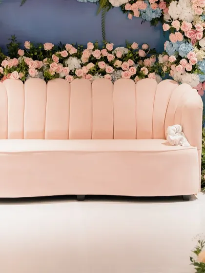 A close-up of the shell-shaped pink velvet sofa, set against the dreamy pastel floral backdrop. Every element was chosen to contribute to the soft, romantic, and minimal aesthetic of the event.