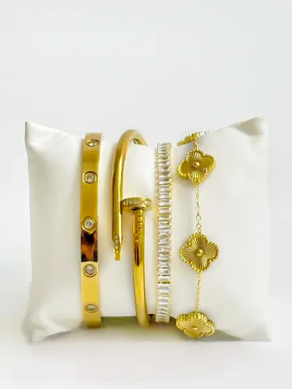 A creative but clean e-commerce shot of gold bracelets on a white cushion against a white background. This is a more stylized approach to catalogue photography.