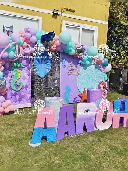 Another view of the outdoor mermaid-themed stage. This shot highlights the shimmering sequin and scale-patterned backdrops, along with the custom marquee letters and balloon garlands.