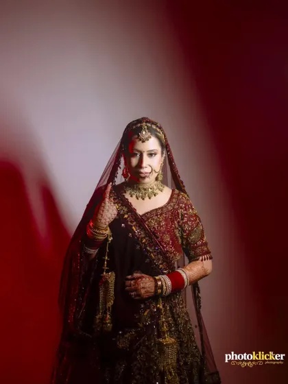 A classic portrait of the bride in her deep red lehenga, looking confidently at the camera, captured with studio-style lighting.