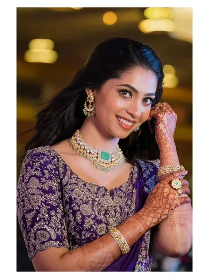 Vidya looking beautiful for her reception. The makeup is elegant and timeless, with a focus on clean skin and defined eyes that complement her intricate henna design.