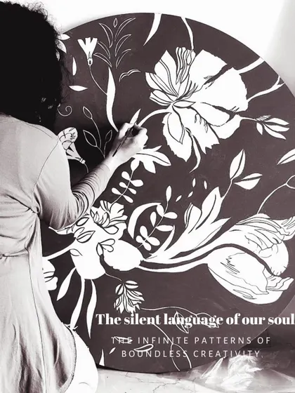 Working on a large, round canvas with a monochrome floral pattern. This piece explores the silent language of creativity through the infinite, intertwined patterns of nature, created with bold white on a dark background.