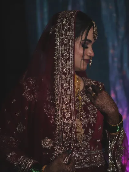 A side profile showcasing the detailed work on the dupatta and the elegant way it frames her face. The makeup is soft yet defined, perfect for a traditional bride.
