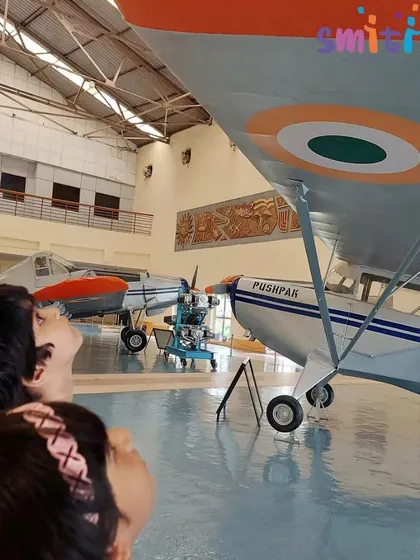 Two children gaze up at a Pushpak trainer aircraft, their faces filled with wonder. The museum visit sparked their curiosity about science and engineering.