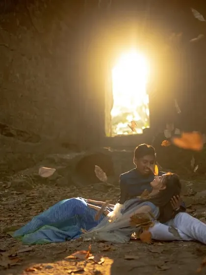A magical and cinematic shot inside a coastal cave, with golden light and falling leaves creating a fairytale atmosphere. This is a unique location for an Alibaug pre-wedding shoot.