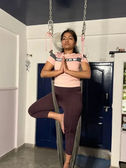 A student finding her balance in aerial Tree Pose. The hammock requires you to engage your core in a different way to maintain stability.