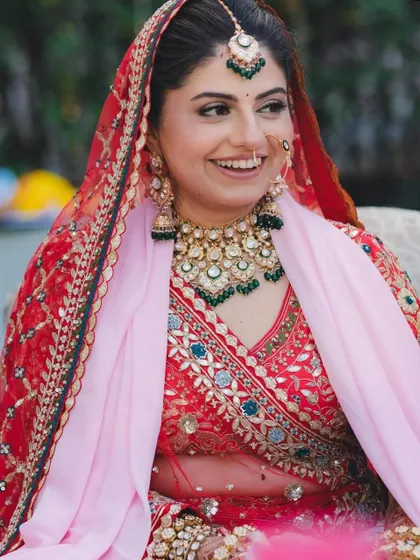 A candid, happy shot of a bride during her wedding festivities, wearing a red and pink lehenga from my rental collection.