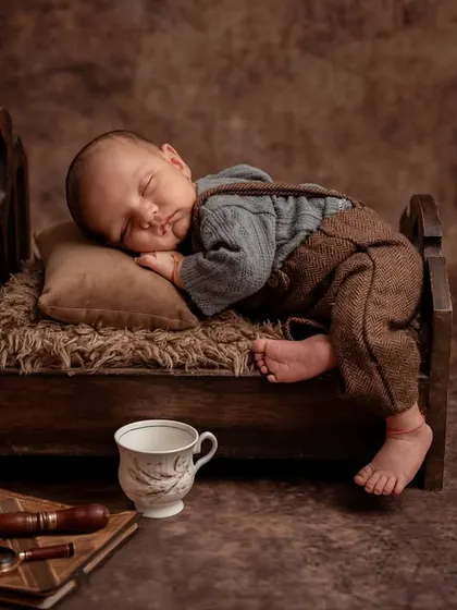 Dreaming of cookies. This adorable setup features a newborn sleeping on a miniature bed with a jar of cookies nearby, creating a sweet and whimsical scene.