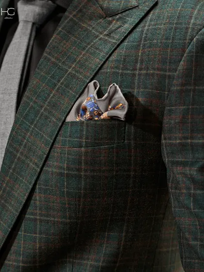 A close-up on the details of the green checked suit. The texture of the fabric, the subtle pattern, and the perfectly chosen pocket square all contribute to its refined character.