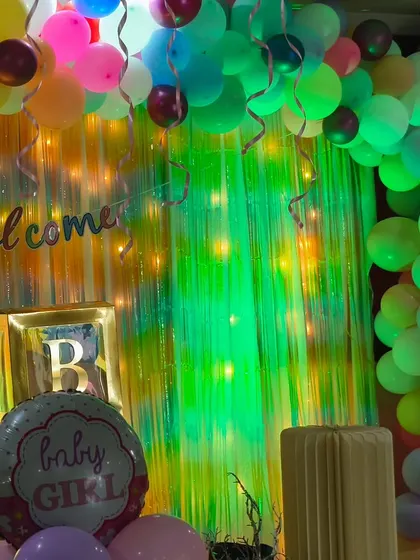 A closer look at the welcome setup for Kathika's celebration. The soft green lighting on the shimmer curtain and the pastel balloons create a dreamy and enchanting ambiance.