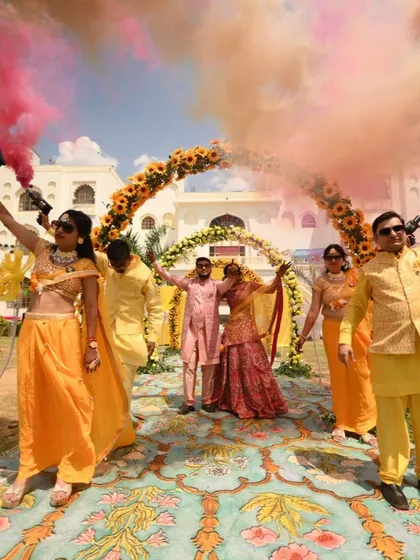A fun Haldi entry with the couple and their family walking under an arch of hands and colorful smoke.