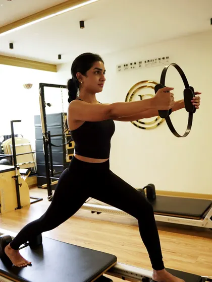 Here we're combining a lunge on the reformer with the resistance of the Pilates ring. This full-body movement targets your glutes, legs, and upper body while demanding constant core engagement.