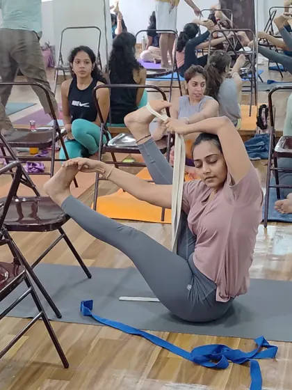 Using a belt and chair to work towards a leg-behind-the-head posture. We use props to safely explore advanced asanas.