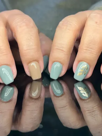 A calming and earthy manicure with a mix of sage green and beige nails, accented with delicate gold leaf art.