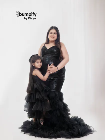 A beautiful moment between a mother and daughter, both in matching black gowns, as they await the new addition to their family.