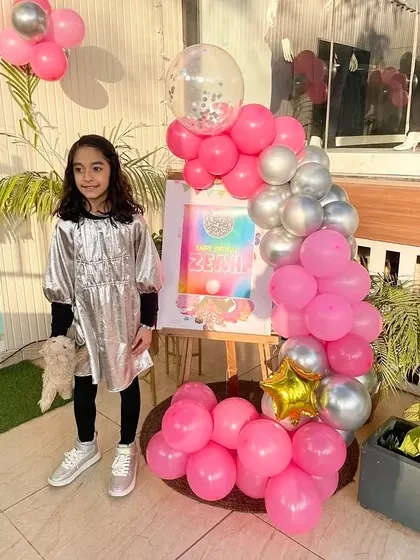 A personalized welcome easel with a pink and silver balloon garland, making the birthday girl feel special from the moment she arrives.