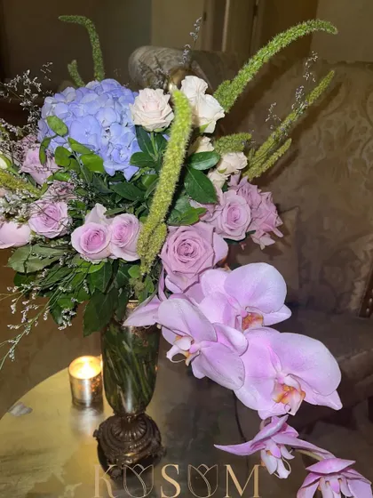 Quiet but opulent. This gorgeous assortment of lilac Phalaenopsis orchids, roses, and hydrangeas, accented with green amaranthus, creates a look of understated luxury.