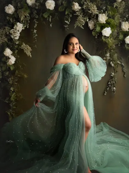 This portrait captures such a happy expression. The mom-to-be is framed by a floral arch, wearing a beautiful pearl-studded green gown.