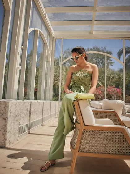 Lounging in luxury. This shot showcases the full Oscar de la Renta look, including the mini Hermès Kelly bag, in a beautiful, light-filled conservatory.