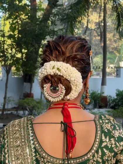 A close-up of the bridal bun, showing the intricate detail of the fresh flower gajra and hair accessory.