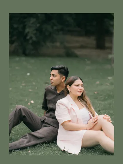 A serene portrait of a couple sitting back-to-back on the grass. This thoughtful pose, combined with the natural setting, creates a calm and contemporary pre-wedding photo.